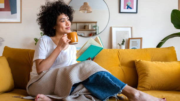 Mujer tomando cafe sentada con un libro en su mano 