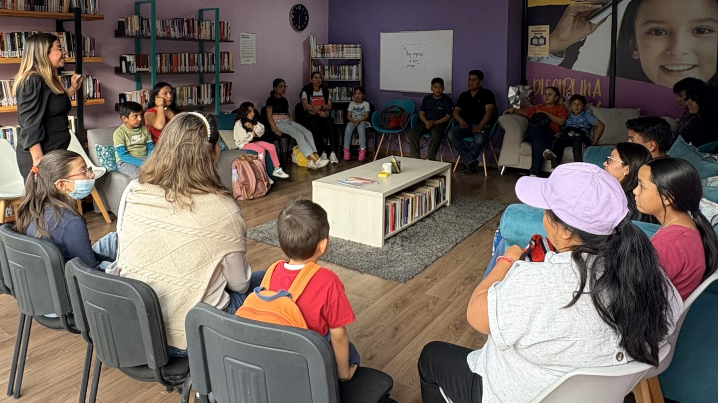 Grupo de personas niños y adultos en un salón de clases leyendo un libro