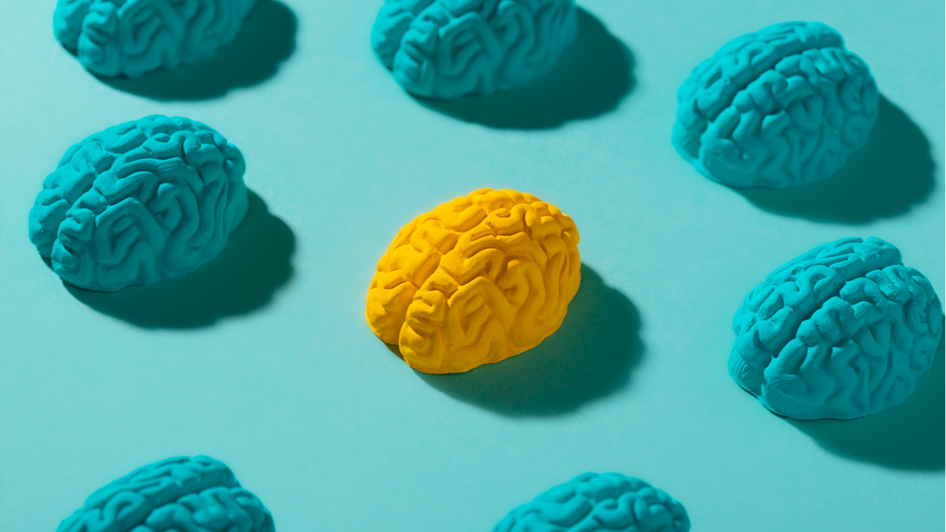 Cerebros de colores sobre fondo azul, con un cerebro amarillo destacando entre cerebros azules, simbolizando pensamiento diferente o aprendizaje activo